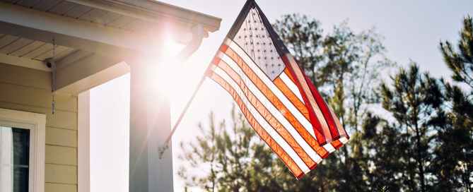 American flag hangs outside a house with the sun shining