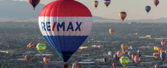RE/MAX Balloon and other hot air balloons flying over city