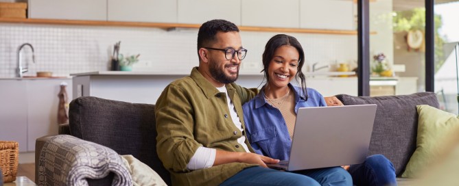 Two people sitting on a couch using a computer