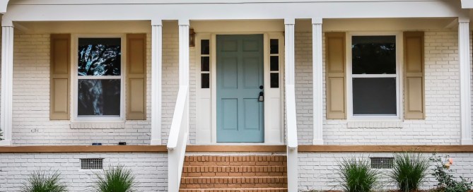 White house with tan shutters and a blue front door.