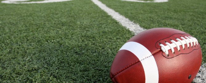 Brown football laying on a green grassy field